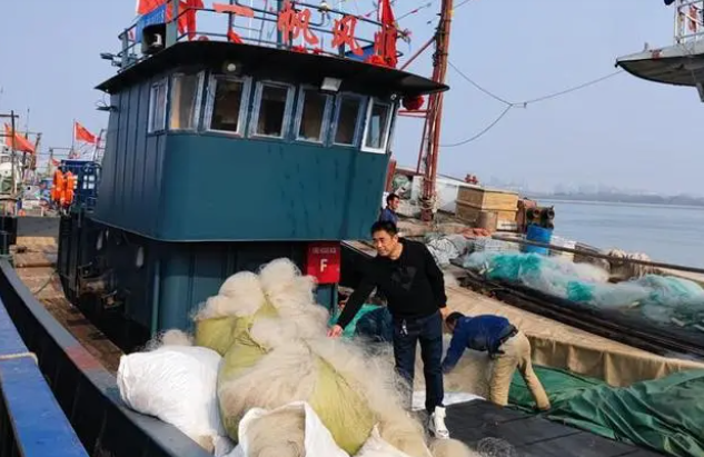 北塘漁港漁戶(hù)吳立民站在一艘剛剛回港的漁船上,向岸上的人們介紹自己的新船。